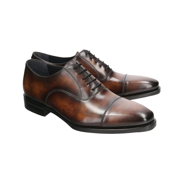 Chestnut patina cap-toe Oxford shoes in full-grain Italian leather with square toe, closed channel stitching, and blue soles. Handmade in Spain.