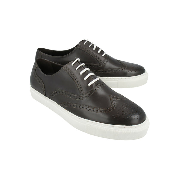 Gray leather sneakers with brogue wingtip design and white rubber soles, handcrafted in Portugal for refined casual style and comfort.