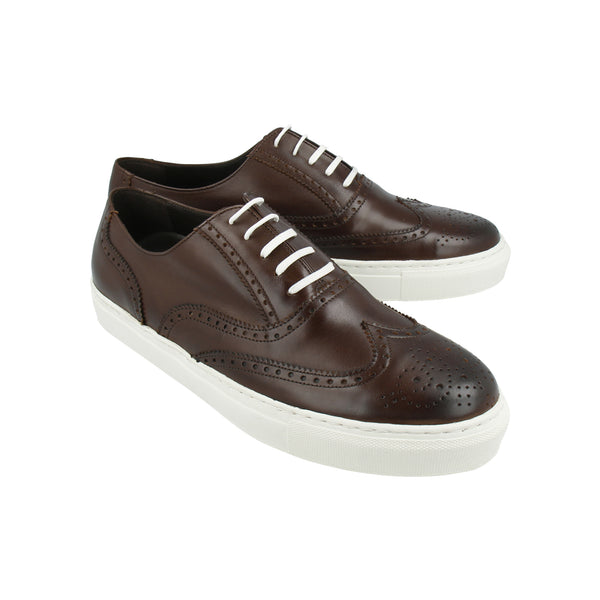 Walnut brown leather sneakers with brogue wingtip detailing and white rubber soles, handcrafted in Portugal for elevated casual style.