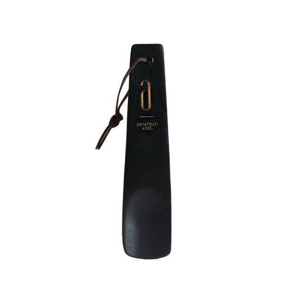 Compact wooden travel shoe horn in black with leather loop, ideal for on-the-go ease and stylish shoe care. Measures 16.5cm.